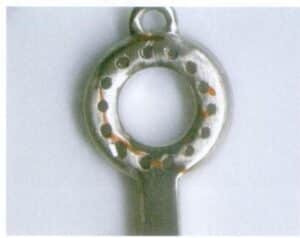 L'illustration 7-45 montre que les trous décoratifs du pendentif ne sont pas tous de la même taille. L'illustration 7-46 montre le goujon cassé sur le pendentif.