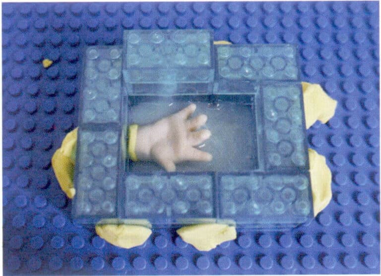 5. Pour the evenly mixed silicone into the wooden mold; at this time, only pour in half the amount of silicone, and then stick the prepared model to one side of the mold; part of the model needs to touch the silicone and be careful not to touch the bottom and sides of the mold; the model must be at least 6 mm away from the bottom to avoid perforation of the silicone mold after it solidifies.