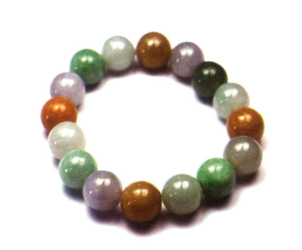 Figur 3-2-2 Färgrik jadeit (De enskilda jadeitpärlorna i armbandet har en mängd olika färger, bland annat grålila, orangegul, oljegrågrön, blågrön och gulgrön. Färgerna på varje pärla är ganska jämna).