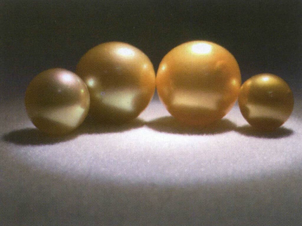 Şekil 4-2-6 Sarı inciler: soldaki iki tanesi göze çarpmayan açık yeşil tonlu doğal altın incilerdir; sağdaki iki tanesi ise neredeyse görünmez bir tonlu boyalı altın incilerdir.