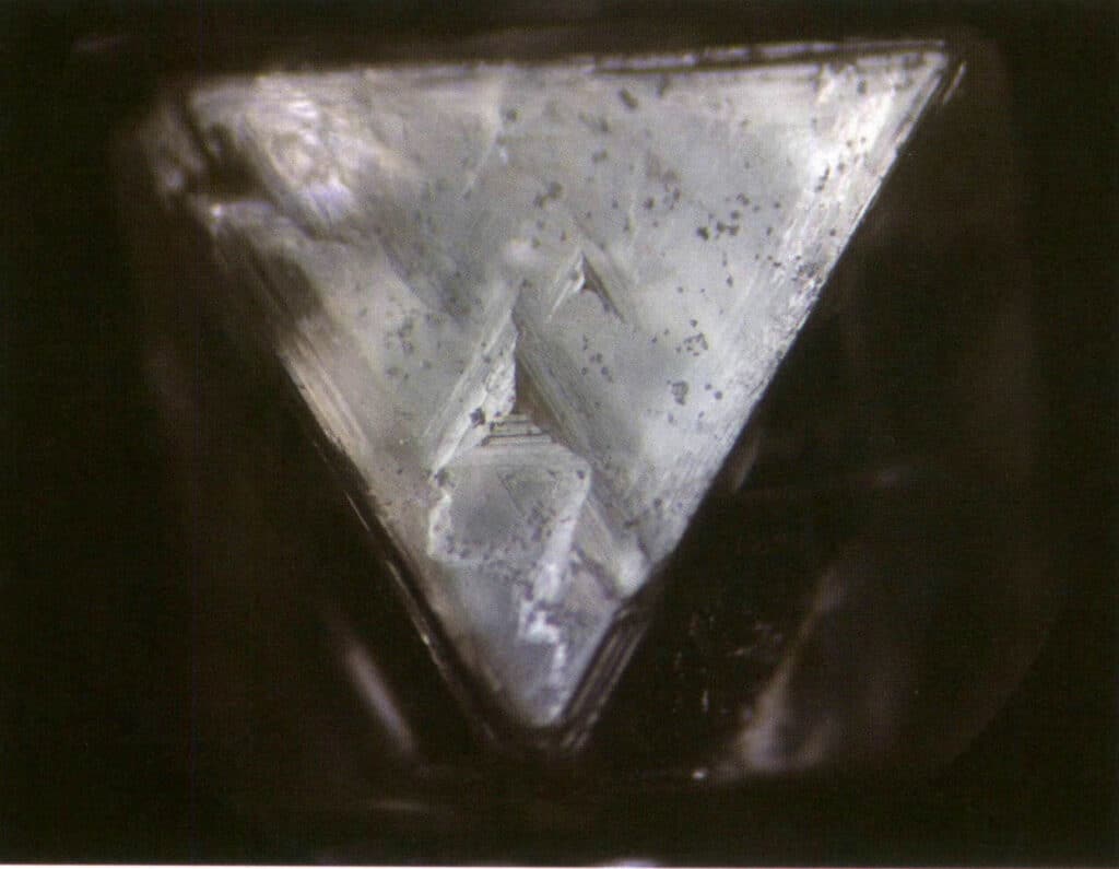 Рисунок 2-1-33 Видимые перевернутые треугольные ямки на октаэдрическом кристалле алмаза