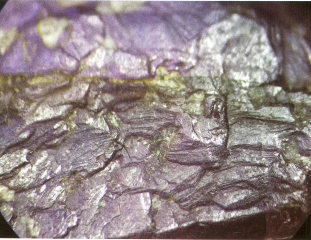 Рисунок 2-1-36 Природная треугольная фигура травления в рубине (обычные горизонтальные полосы в рубинах, линии роста параллельны ромбоэдрическому направлению, природные травления в треугольной или шестиугольной форме)