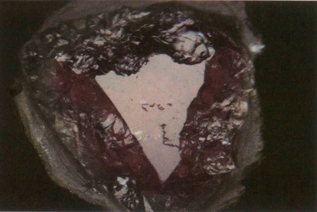 الشكل 2-3-35 مقارنة بين اللمعان الدهني (على الحواف غير المستوية) واللمعان الزجاجي (في منطقة التظليل المثلثة تقريباً) لسطح التورمالين المكسور تحت الضوء المنعكس