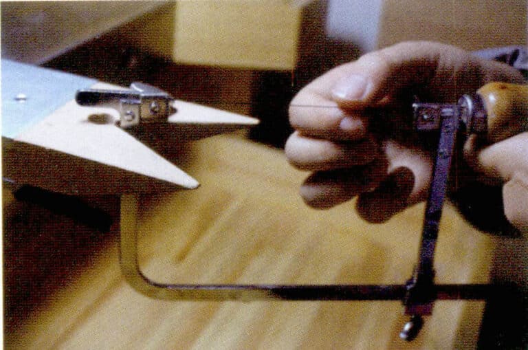 ② Сядьте, открутите винт на другом конце пильной рамы, отрегулируйте другой конец пильного полотна, чтобы оно вошло в паз, прижмите затянутый конец пильной рамы к верстаку и упритесь грудью в ручку пильной рамы, затем затяните гайку. Наконец, медленно ослабьте давление на рукоятку; это сделает установленное пильное полотно более плотным, но также будьте осторожны с натяжением, так как слишком сильное натяжение может привести к поломке пильного полотна.