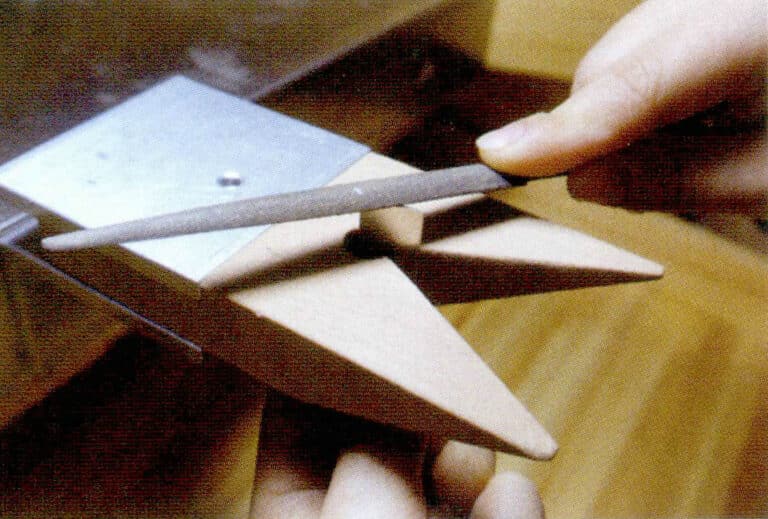 ① Держите напильник в одной руке, а другой стабилизируйте металл на верстаке, если металлическая деталь слишком мала для контроля пальцами, для фиксации можно использовать деревянный зажим.