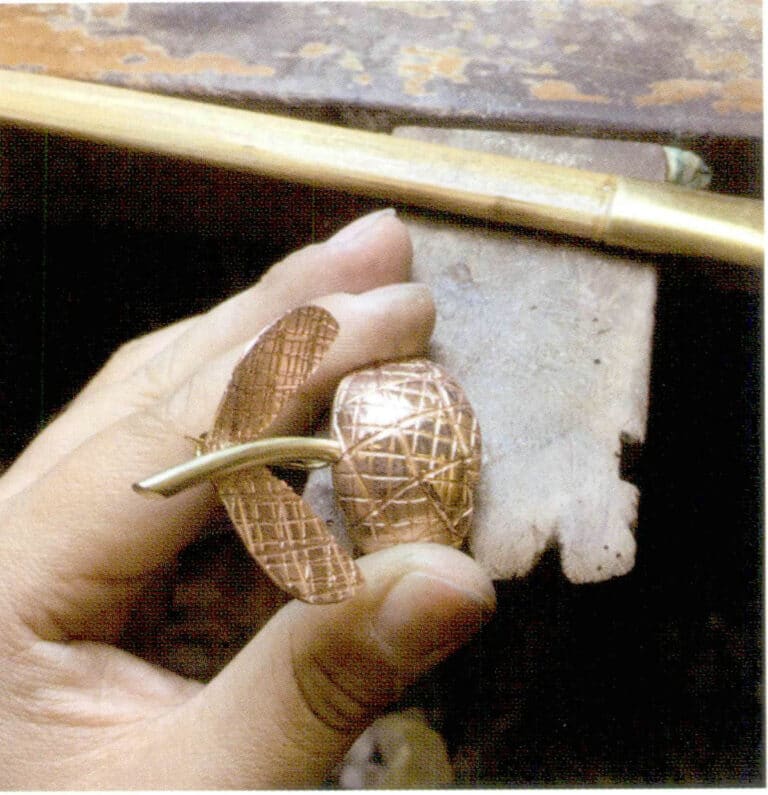 1. Using dome craft to hammer the prepared textured metal piece into a 1/4 arc before welding.