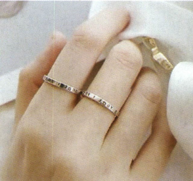 The same hand wearing a silver ring (left) and a gold ring (right)