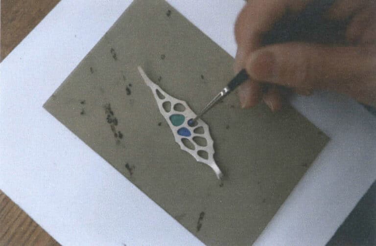 Figure 7-19 Filling enamel glaze into a metal frame laid flat on a mica sheet